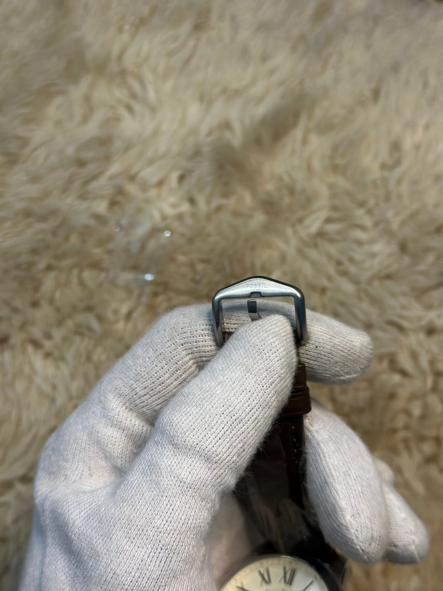 Hand wearing a gray glove holding a metal buckle over water