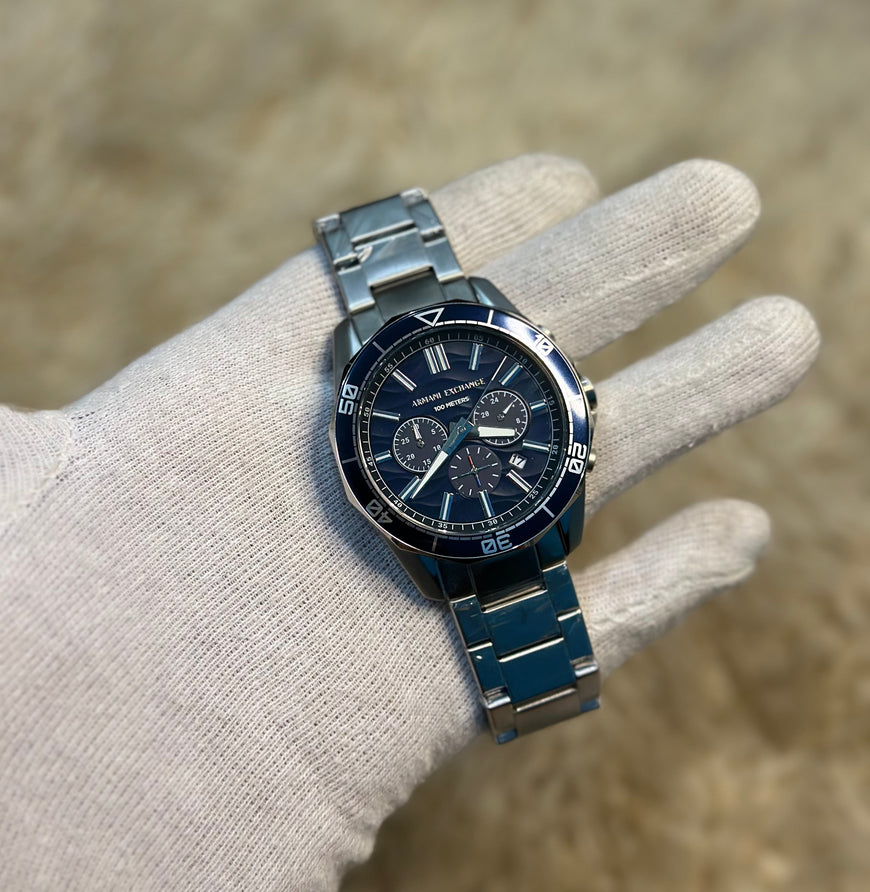 Silver watch with a dark face on a gloved hand against a blurred background