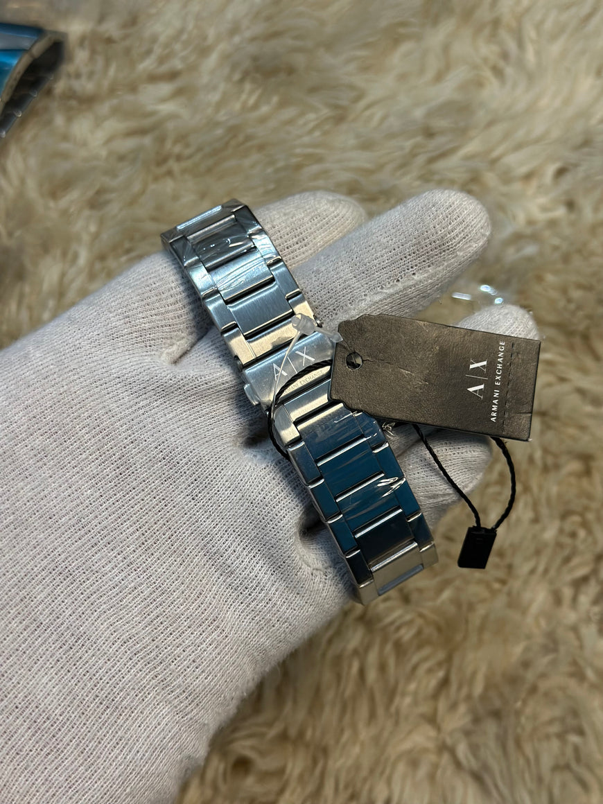 Silver watch with a visible brand tag on a textured surface